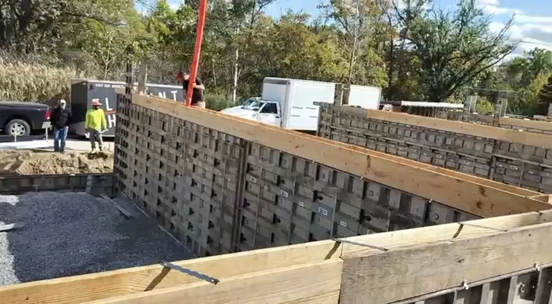 Crew setting footing wall forms with lumber bracing over a gravel footing trench