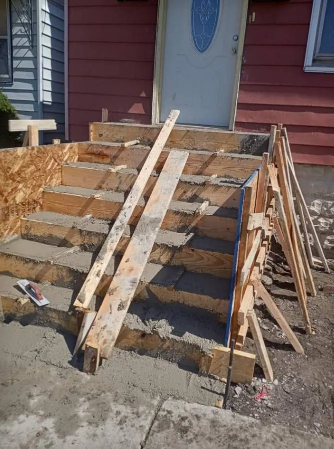 Concrete steps poured in wood forms leading to a front door, plywood side forms in place