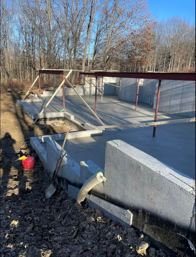Basement slab poured inside tall foundation walls with steel bracing and wood forms still in place