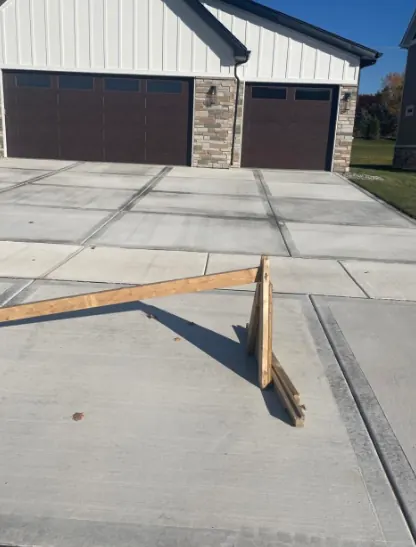 Freshly poured concrete driveway with control joints in front of a three-car garage