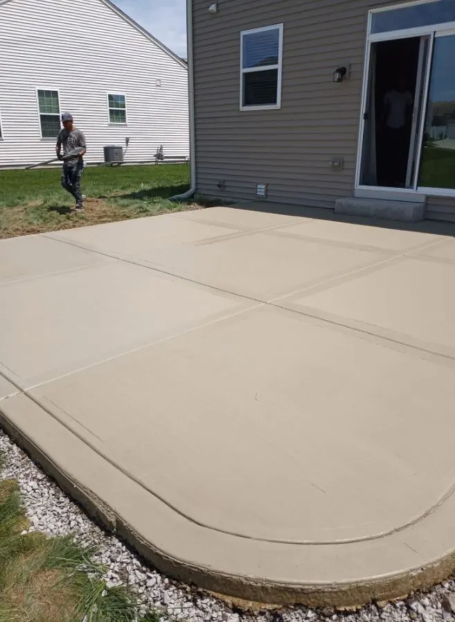 Rounded-edge broom-finished concrete patio behind a two-story house