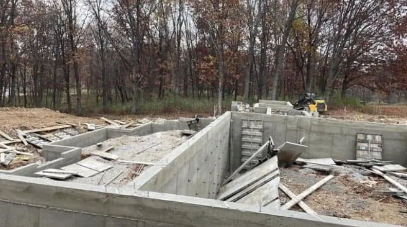Finished concrete footing walls for a foundation with formwork removed, wooded lot in fall
