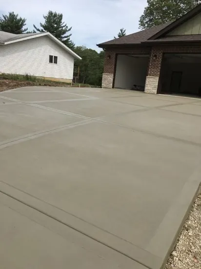 Finished concrete driveway leading to a brick and stone three-car garage